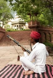 Street musician in his traditional dress playing music instrument, Rajasthan, India.